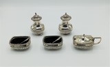 Condiment set with 2 shakers, 2 salt cellars and 1 mustard pot. The inside of the salt cellars and the mustard pot is made of blue glass. Includes 2 spoons. Sterling silver. Birmingham hallmarks for the year 1913. 336g., 9,5 cm, 1913