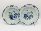 Par de pratos Companhia das Índias do período Qianlong (China, 1736-1795) com decoração floral azul e branca. Ligeiras esbeiçadelas. Um com pequeno restauro., 23,5 cm, 1736-1795